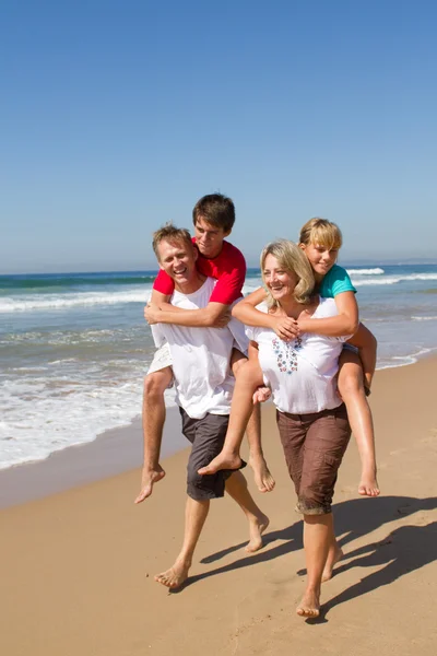 Gelukkige familie piggyback op strand — Stockfoto