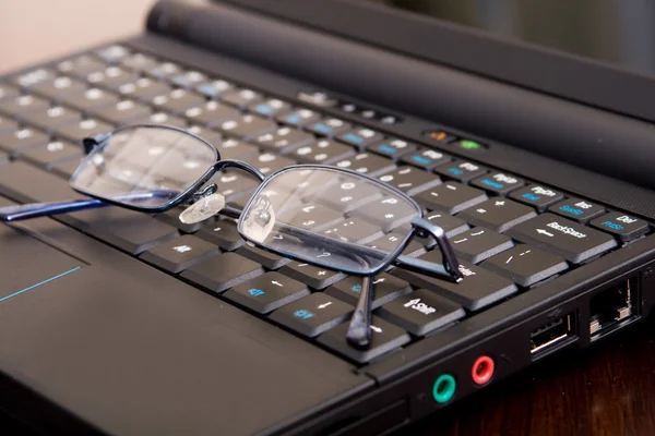 黑色笔记本计算机上的眼镜 — 图库照片