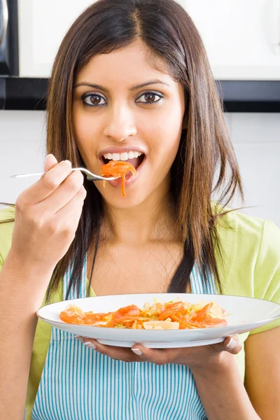 Ung kvinna provsmakning mat i köket — Stockfoto
