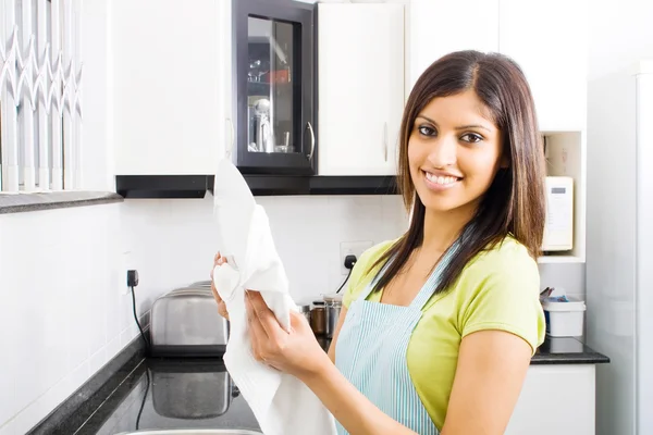 Jovem mulher secando pratos na cozinha — Fotografia de Stock