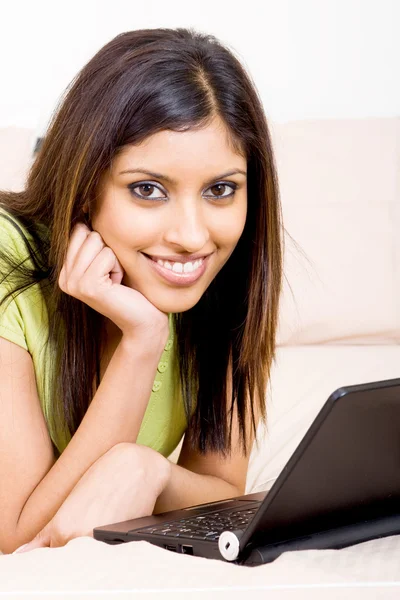 Young woman relaxing in bed with laptop — Stock Photo, Image