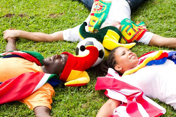 Skupina fotbalových fanoušků, ležící na trávě — Stock fotografie