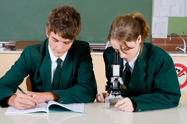 Estudantes de escola alta usando microscópio — Fotografia de Stock