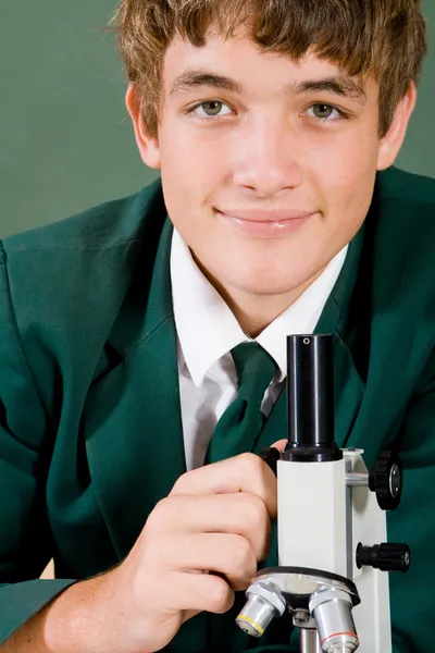 Menino do ensino médio com microscópio — Fotografia de Stock
