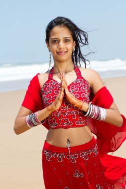 Young indian woman in traditional sari on beach praying clipart