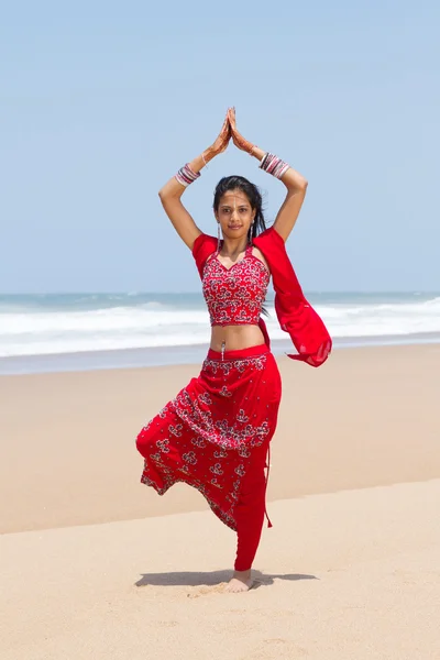 Traditional Indian woman doing yoga on beach — Stock Photo, Image