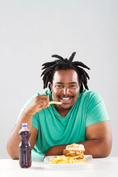 Fat african american man eating chips — Stock Photo, Image