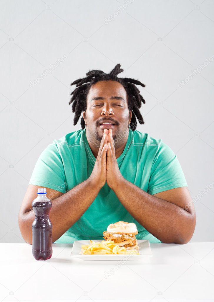Overweight african american man pray before eating a meal