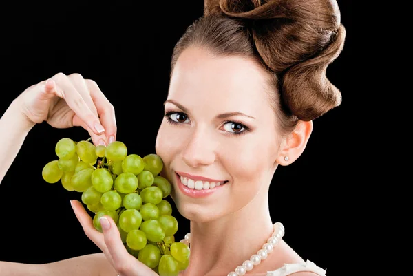 Mooi slank meisje houdt van een groene druiven — Stockfoto