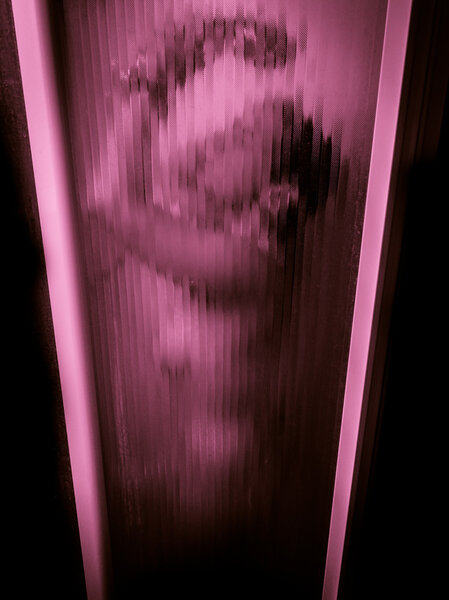 Женщина принимает душ за стеклянной дверью
