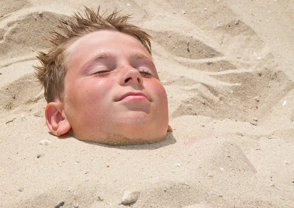 Menino enterrado na areia — Fotografia de Stock