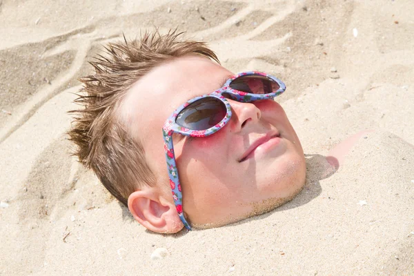 Мальчик похоронен в песке — стоковое фото