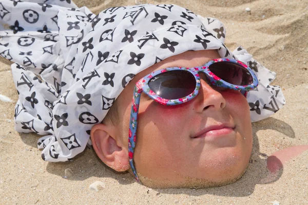 Boy buried in sand — Stockfoto