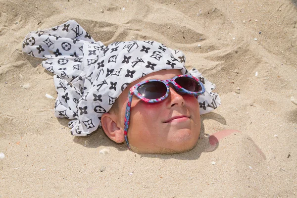Boy buried in sand — Stockfoto