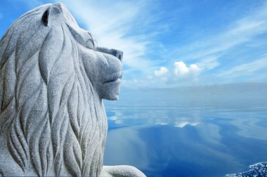 Stone statue of a lion over blue lake clipart