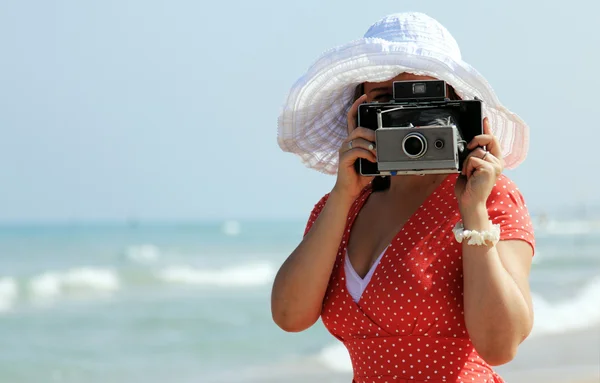 Junges Mädchen im roten Kleid mit alter Kamera — Stockfoto