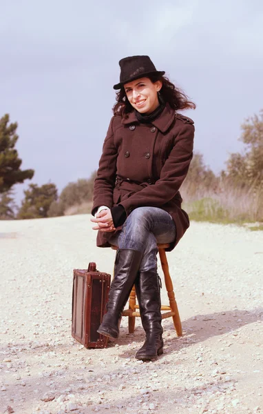 Mädchen mit einem Koffer sitzt auf einem Hocker — Stockfoto