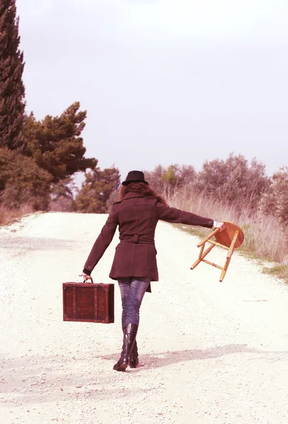 Дівчина з валізою сидить на табуреті — стокове фото