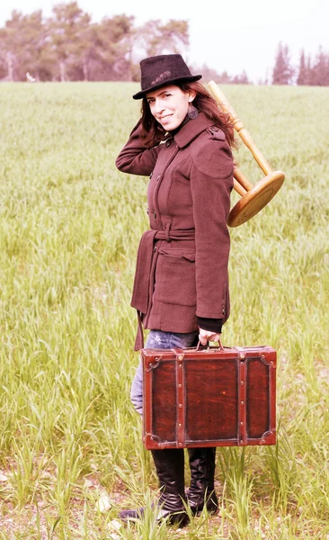 Girl with a suitcase sitting on a stool — Stock Photo, Image