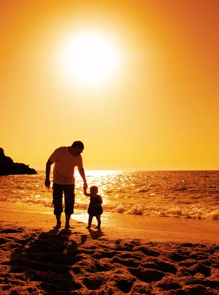 Far och dotter spelar på stranden vid solnedgången — Stockfoto