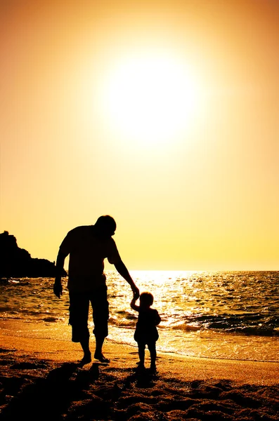 Far och dotter spelar på stranden vid solnedgången — Stockfoto