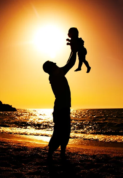 Vader en dochter spelen op het strand bij zonsondergang — Stockfoto