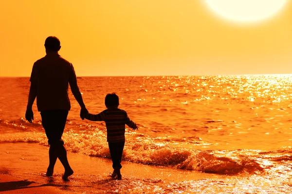 Enfant avec son père en mer au coucher du soleil Images De Stock Libres De Droits
