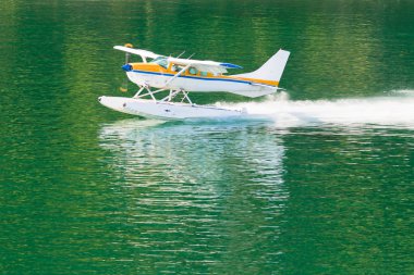 Aircraft seaplane taking off on calm water of lake clipart