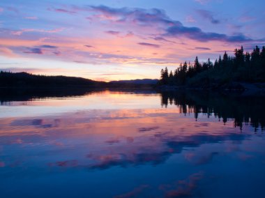 Reflection of sunset sky on calm surface of pond clipart