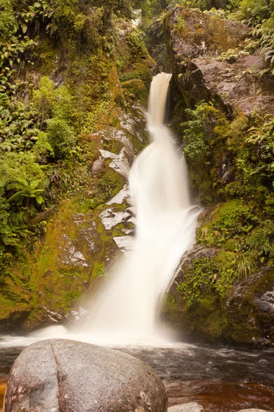 Silky forest waterfall cascading down rocky slope — Stock Photo, Image