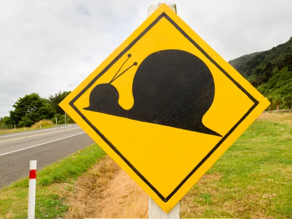 Gefälschte Aufmerksamkeit Kauri Schnecke überquert Verkehrsschild — Stockfoto