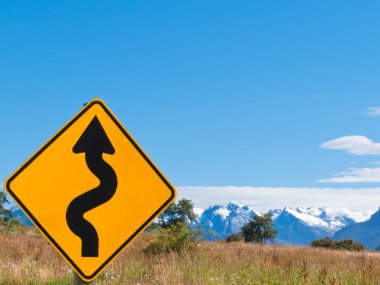 Wavy arrow roadsign and snowy mountain peaks clipart