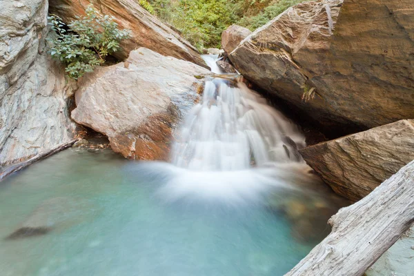 Pequena cascata cascata sobre rochas em lagoa azul — Fotografia de Stock