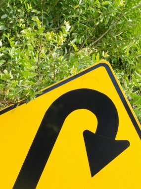 Think green - U-turn roadsign in lush vegetation clipart