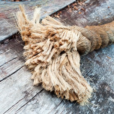 Frayed end of sisal rope lying on weathered wood clipart