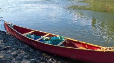 River shore and red canoe in green water clipart