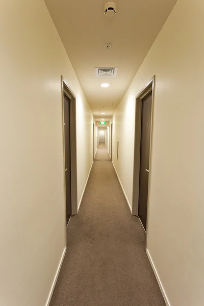 Довгий коридор з готельними дверима та вихідним знаком — стокове фото