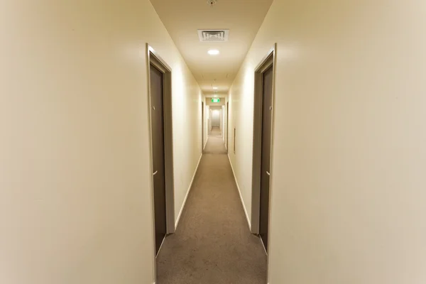 Langer Korridor mit Hotelzimmertüren und Ausstiegsschild — Stockfoto