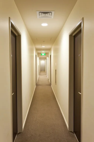 Long couloir avec portes de chambre d'hôtel et panneau de sortie — Photo
