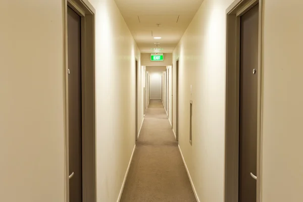 Long couloir avec portes de chambre d'hôtel et panneau de sortie — Photo