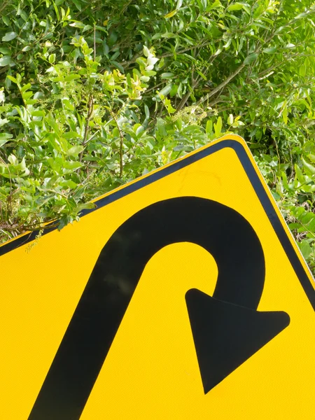 Pensar verde - sinal de estrada em U-turn em vegetação exuberante — Fotografia de Stock