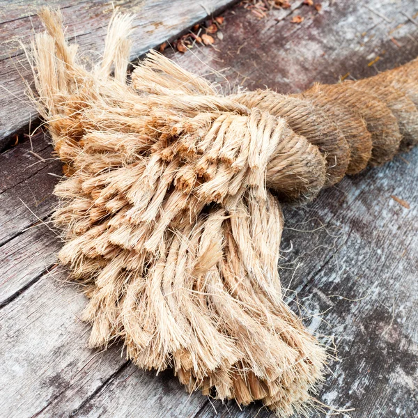 Fim desgastado de corda de sisal deitada em madeira intemperizada — Fotografia de Stock