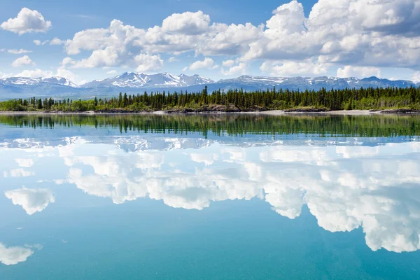 Yukon wilderness cloudscape reflected on calm lake Rechtenvrije Stockfoto's