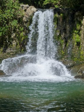 Waterfall casdcading over rocks into a calm pool clipart