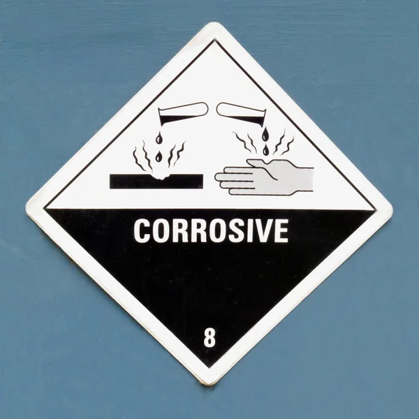 Sinal de advertência do símbolo de perigo corrosivo no azul — Fotografia de Stock