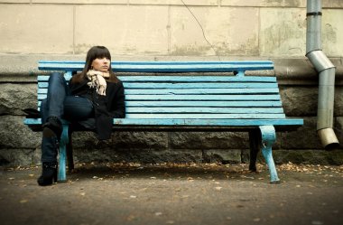 Siyah palto bankta oturan genç kadın