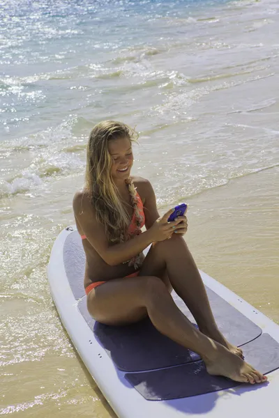 Young woman in bikini on paddle board texting — Stock Photo, Image
