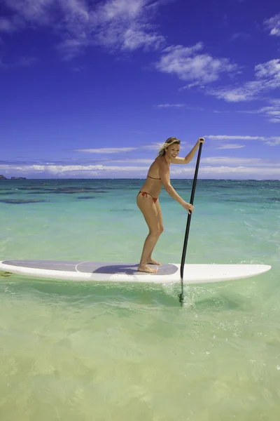 Prachtige blond meisje in een bikini op haar bord peddel — Stockfoto