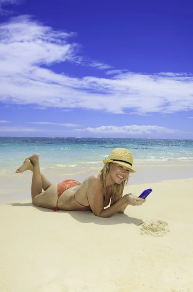 Prachtige blond meisje in het texting bikini op het strand — Stockfoto
