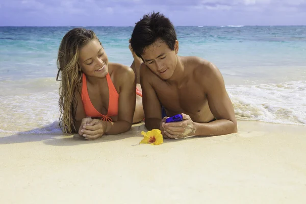 Casal na praia em Havaí com seu telefone celular — Fotografia de Stock